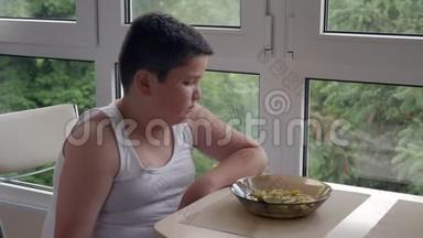 无聊的小胖子在厨房里吃饭，吃一大勺汤，儿童肥胖和暴饮暴食